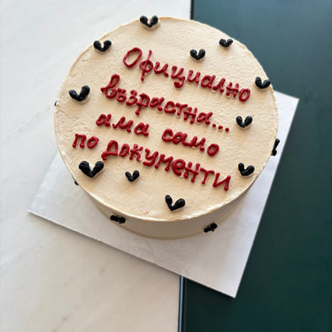 Round cream-coloured cake with the message 'Officially an adult... but only on paper'