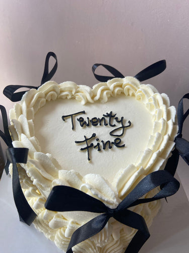 Бяла торта сърце с декоративни панделки, кремав кант и надпис "twenty fine".