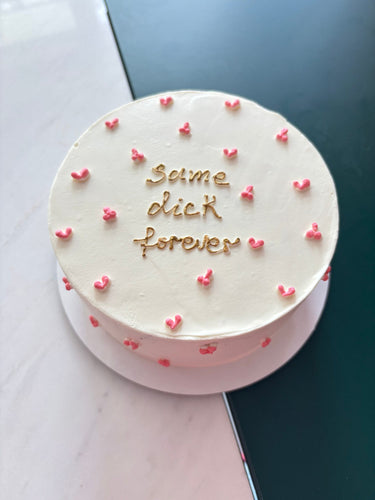 Кръгла бяла торта с надпис "Same dick forever" в златни букви.