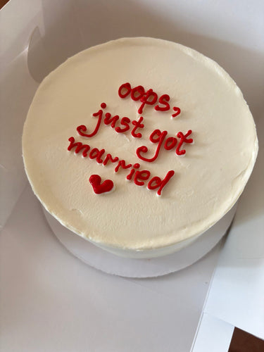 Кръгла бяла торта с надпис 'oops, just got married ♥'