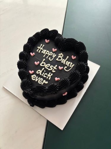 Черна торта във форма на сърце с кремав кант и надпис Happy Bday best dick ever