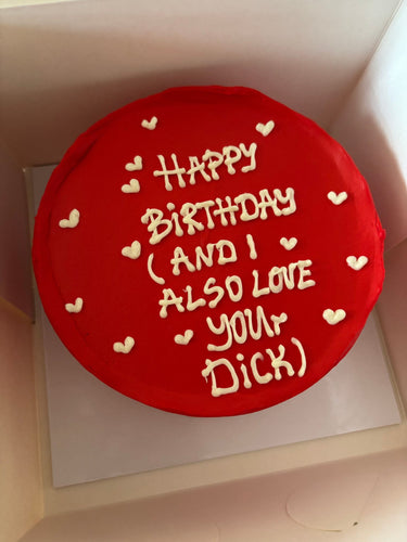 Кръгла червена торта с надпис 'Happy Birthday (and I also love your Dick)' в бял или контрастен цвят.