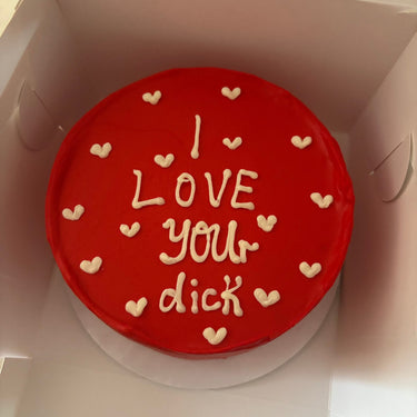 Кръгла червена торта с надпис "I LOVE you dick" отгоре, без допълнителна украса.