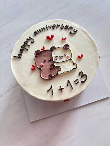 Кръгла бяла торта с надпис 'happy anniversary 1+1=3' и ръчна рисунка върху глазурата.