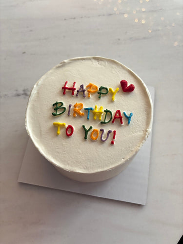 Кръгла бяла торта с шарена рисунка и надпис HAPPY BIRTHDAY TO YOU!