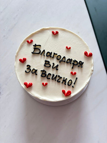 Бяла кръгла торта с надпис "Благодаря ви за всичко!" и декорация със сърца.
