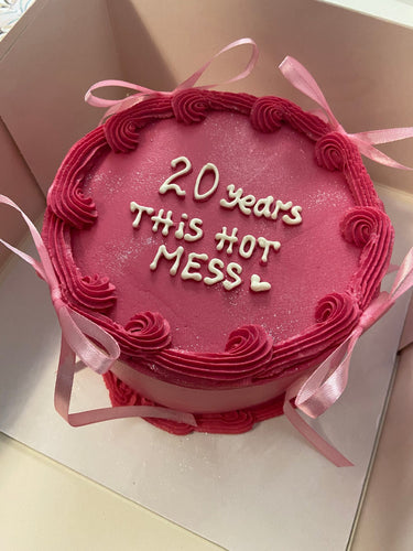 Кръгла розова торта с кремав кант и панделки, надпис '20 years This Hot MESS♡'