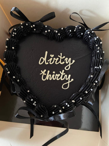 Черна торта сърце с надпис "dirty thirty", украсена с перли, панделки и кремав кант.