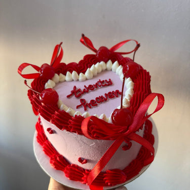 Pink heart cake with a cream border, ribbons and cherries, message twenty heaven