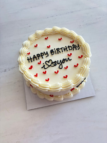 Кръгла кремава торта с кремав кант, червени сърца и надпис HAPPY BiRTHDAY i ♥ you.