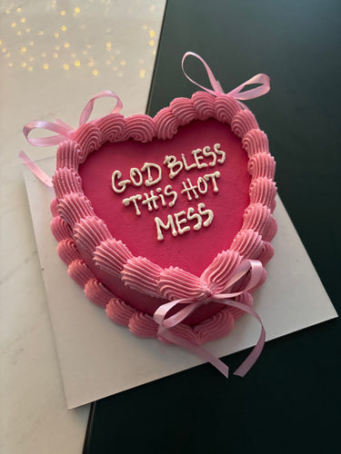 Розова торта сърце с кремав кант, панделки и надпис GOD BLESS THIS HOT MESS
