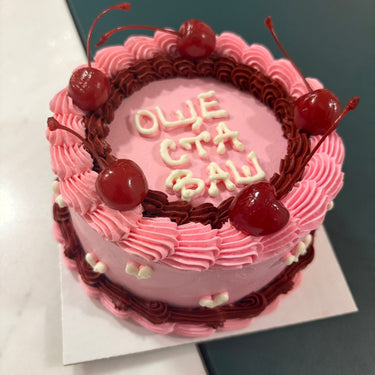 Round pink cake with cherries, cream border and the message "STILL GOT IT"