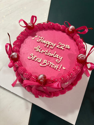 Кръгла розова торта с кремав кант, панделки, черешки и перли, с надпис Happy 22th Birthday SEXY BITCH!