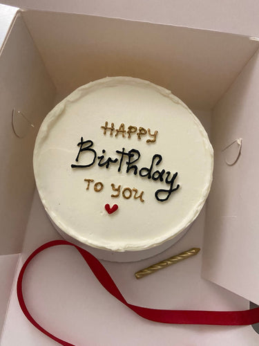 Кръгла бяла торта със златен надпис HAPPY Birthday To you и сърце.