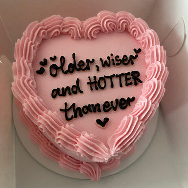 Розова торта сърце с кремав кант и надпис 'older, wiser and HOTTER than ever'