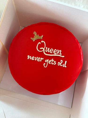 Кръгла червена торта с златен надпис Queen never gets old.