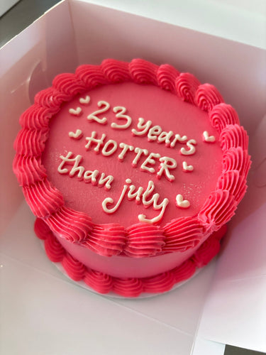 Кръгла розова торта с кремав кант и надпис '23 years HOTTER than july'