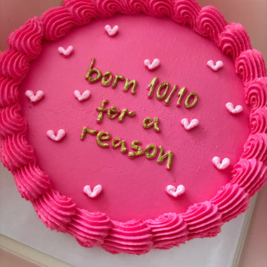 Кръгла розова торта с брокат, кремав кант и златен надпис "born 10/10 for a reason"
