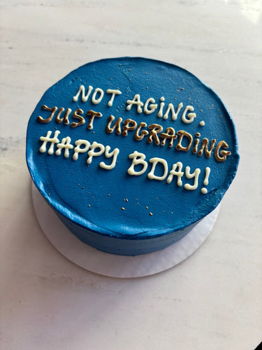 Кръгла синя торта с брокатена украса и златен надпис NOT AGING JUST UPGRADING HAPPY BDAY!