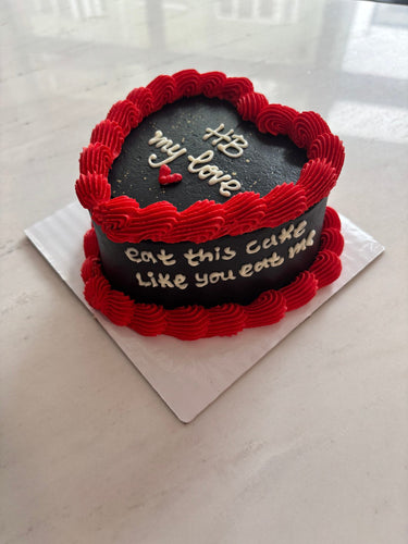 Черна торта сърце с кремав кант по ръба и страничен надпис 'HB my love / eat this cake like you eat me'.