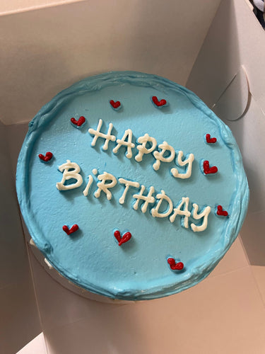 Кръгла торта с бебешко синя глазура, декорирана със сърца и надпис Happy Birthday