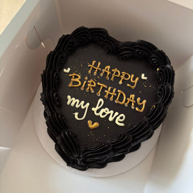 Черна торта във форма на сърце с кремав кант, брокат и златен надпис "Happy Birthday my love".