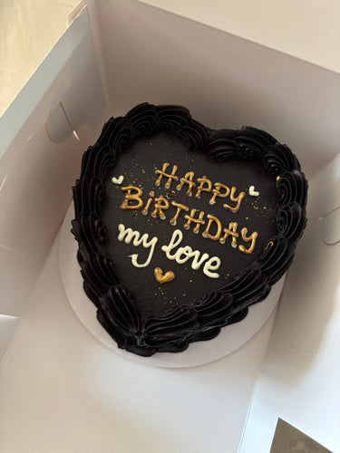 Черна торта във форма на сърце с кремав кант, брокат и златен надпис "Happy Birthday my love".