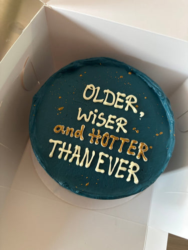 Кръгла морскосиня торта със златен надпис 'OLDER, WISER and HOTTER THAN EVER'
