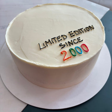 Кръгла кремава торта с рисунка и надпис 'Limited Edition Since 2000'.