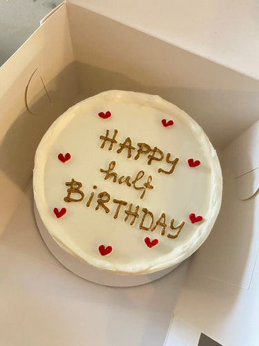 Кръгла бяла торта с надпис Happy half BIRTHDAY в златен цвят
