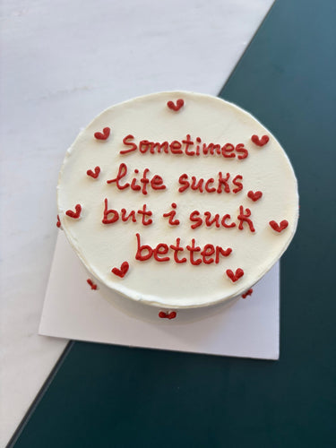 Кръгла бяла торта с надпис Sometimes life sucks but i suck better, без допълнителна украса.