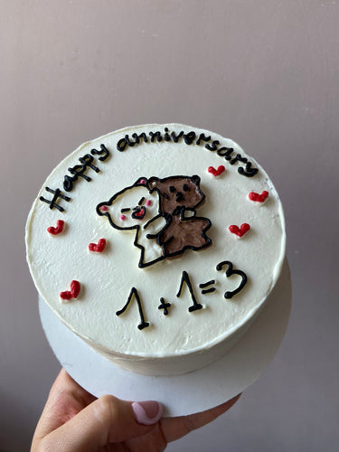 Кръгла бяла торта с рисунка и надпис 'Happy anniversary 1+1=3' за годишнина