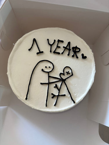 Кръгла бяла торта с декоративна рисунка и надпис '1 YEAR.'