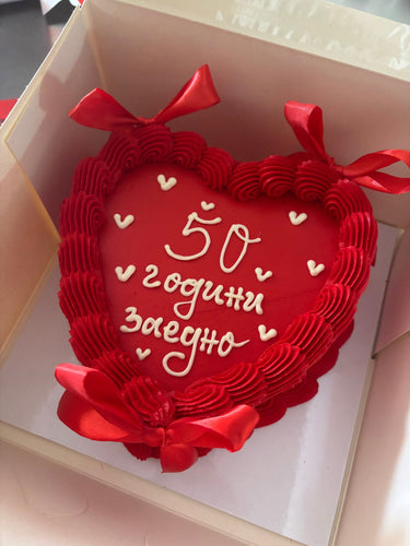 Торта във форма на сърце с червена глазура, панделки и надпис '50 години заедно'