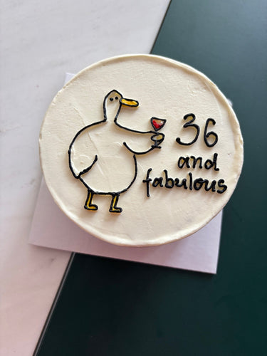 Кръгла кремава торта с рисунка на патица с вино и надпис '36 and fabulous'