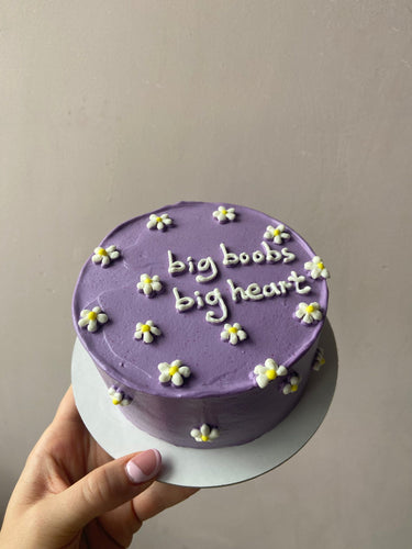 Кръгла люлякова торта с надпис 'big boobs big heart' върху глазурата, без допълнителна украса.