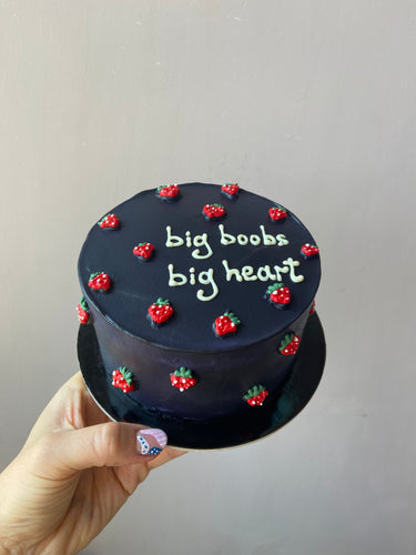 Кръгла морскосиня торта с надпис 'big boobs big heart', украсена с ягоди върху глазурата.