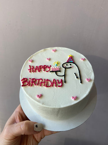 Кръгла бяла торта с нарисуван човек и надпис 'HAPPY BiRTHDAY' отгоре.