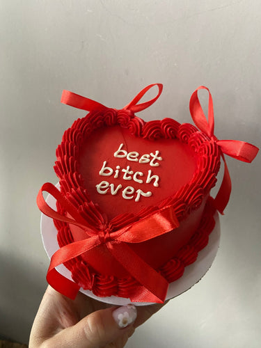 Червена торта сърце с панделки, кремав кант и надпис 'best bitch ever'