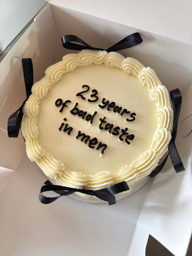 Кремава кръгла торта с панделки, кремав кант и надпис '23 years of bad taste in men'