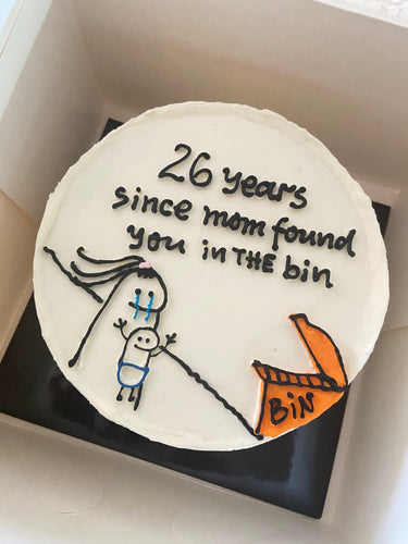 Кръгла бяла торта с рисунка и надпис '26 years since mom found you in THE bin'