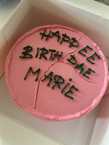 Кръгла розова торта с надпис 'HAPPEE BIRTHDAE MARIE' в стил Хари Потър.