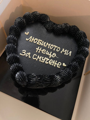 Сърцевидна черна торта с брокат, кремав кант и надпис 'любимото ми нещо за смучене'.