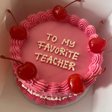 Кръгла розова торта с черешки, кремав кант и надпис 'To my Favorite Teacher'.