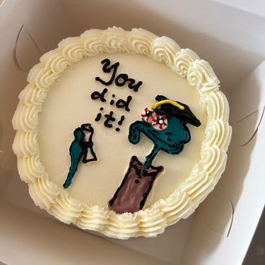 Кръгла бяла торта с рисунка на Squidward, кремав кант и надпис 'You did it!'