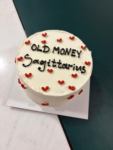 Кръгла бяла торта с надпис 'OLD MONEY Sagittarius' за зодия Стрелец