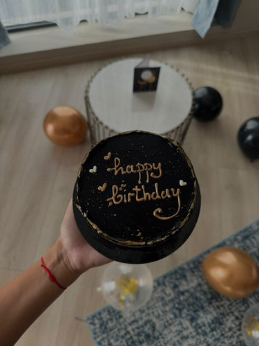 Кръгла черна торта с брокат и златен надпис 'happy birthday'