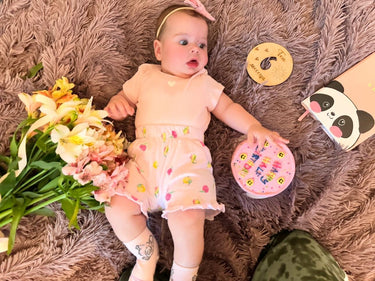 Кръгла бебешко розова торта с рисунки на усмивки и надпис 'Happy Birthday'.