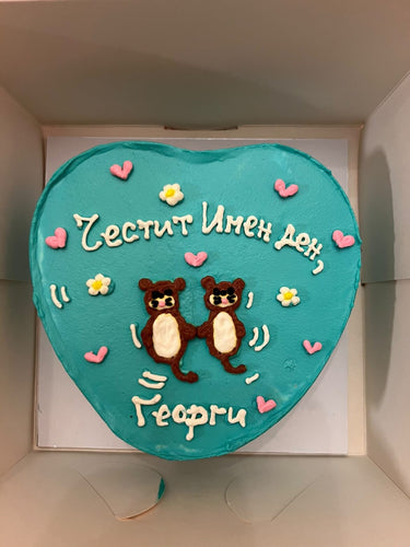 Торта сърце в ментов цвят с рисунка на видри и надпис 'Честит Имен ден, Георги'.