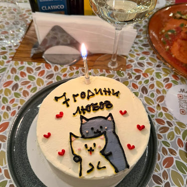 Round cream cake with a hand-drawn design and the inscription '7 years of love', for an anniversary.